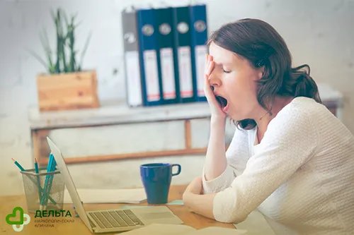 Девушка зевает за рабочим столом